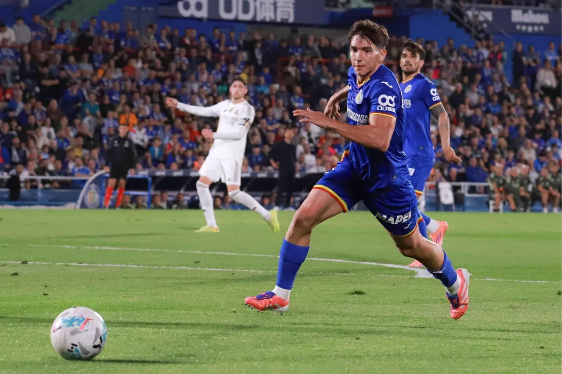 Grafika przedstawiająca piłkarza biegnącego za piłką.